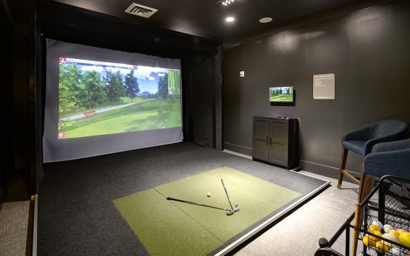 a room with a large screen and a table with a cart and a chair